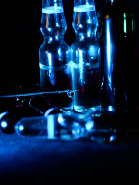 Tıbbi ampuller kapanıyor. Bir sürü ampul. Masada cam ampuller var. İlaç ile dağılmış ampuller.