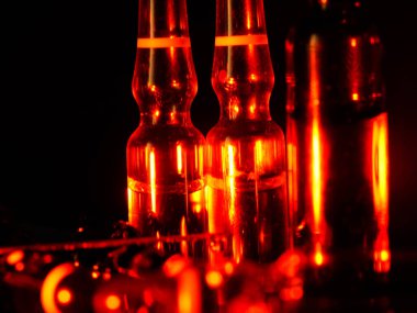 Tıbbi ampuller kapanıyor. Bir sürü ampul. Masada cam ampuller var. İlaç ile dağılmış ampuller.