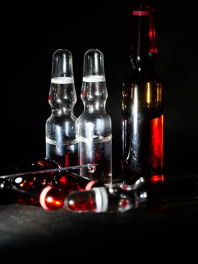 Tıbbi ampuller kapanıyor. Bir sürü ampul. Masada cam ampuller var. İlaç ile dağılmış ampuller.