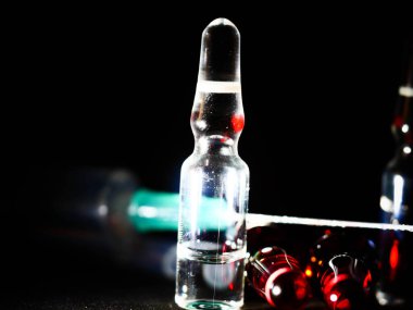 Tıbbi ampuller kapanıyor. Bir sürü ampul. Masada cam ampuller var. İlaç ile dağılmış ampuller.