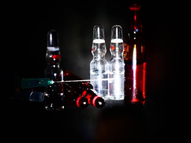 Tıbbi ampuller kapanıyor. Bir sürü ampul. Masada cam ampuller var. İlaç ile dağılmış ampuller.