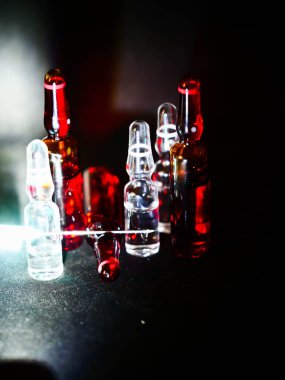 Tıbbi ampuller kapanıyor. Bir sürü ampul. Masada cam ampuller var. İlaç ile dağılmış ampuller.