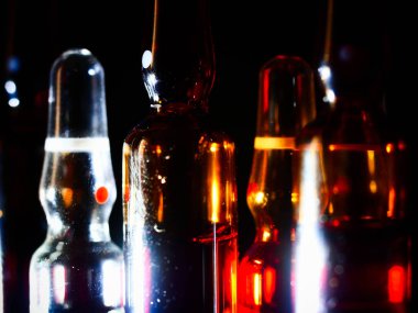 Tıbbi ampuller kapanıyor. Bir sürü ampul. Masada cam ampuller var. İlaç ile dağılmış ampuller.