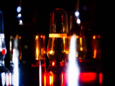 Tıbbi ampuller kapanıyor. Bir sürü ampul. Masada cam ampuller var. İlaç ile dağılmış ampuller.