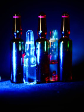 Tıbbi ampuller kapanıyor. Bir sürü ampul. Masada cam ampuller var. İlaç ile dağılmış ampuller.