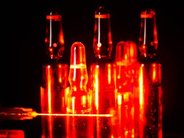 Tıbbi ampuller kapanıyor. Bir sürü ampul. Masada cam ampuller var. İlaç ile dağılmış ampuller.