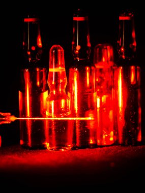 Tıbbi ampuller kapanıyor. Bir sürü ampul. Masada cam ampuller var. İlaç ile dağılmış ampuller.