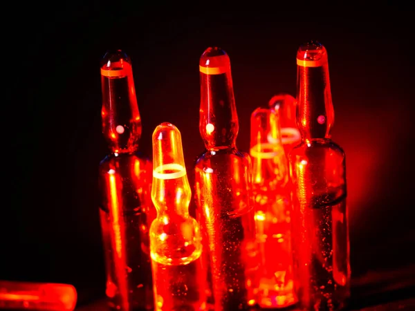 Tıbbi ampuller kapanıyor. Bir sürü ampul. Masada cam ampuller var. İlaç ile dağılmış ampuller.