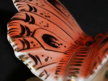 Porselen kelebek figürü siyah arka planda izole edilmiş.