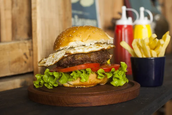 Hamburgare med pommes frites på träbord — Stockfoto