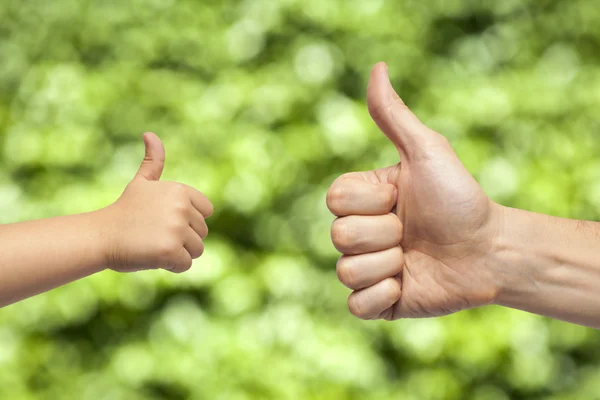 Father and son hands giving like on green background — Stock Photo, Image