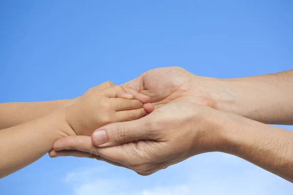 Vater und Sohn halten Händchen auf einem Himmelshintergrund — Stockfoto