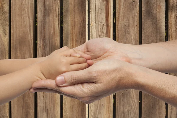 Vater und Sohn halten Händchen auf Holzuntergrund — Stockfoto