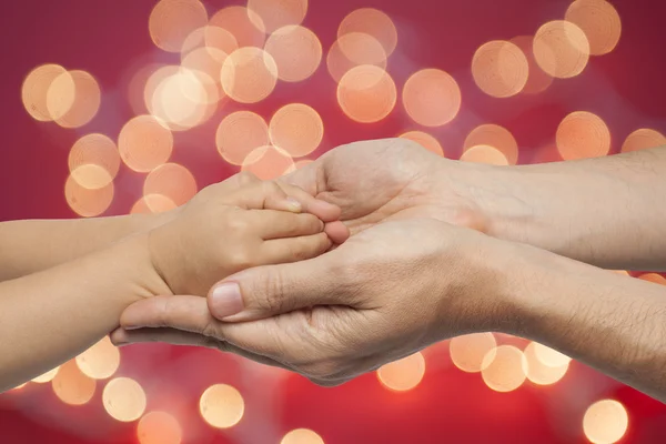 Far och son hand i hand på jul ljus bakgrund. — Stockfoto