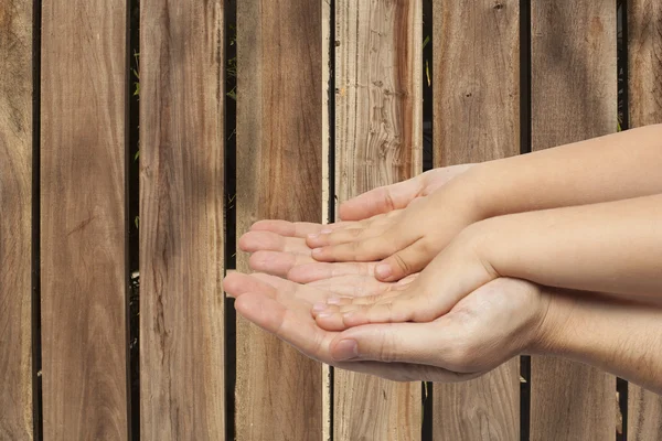 Padre e hijo tomados de la mano sobre fondo de madera —  Fotos de Stock