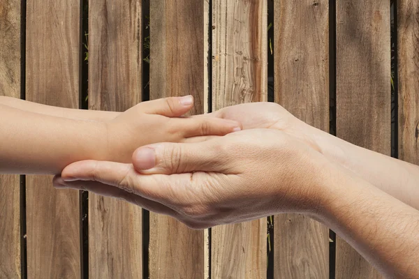 Far och son hand i hand på trä bakgrund — Stockfoto