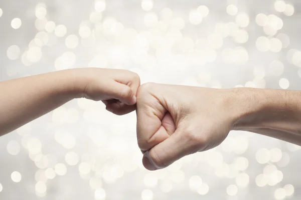 Pai e filho punhos de perfuração para acordo sobre luzes de Natal fundo . — Fotografia de Stock