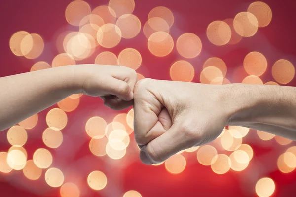 Father and son punching fists for agreement on christmas lights background. — Stock Photo, Image