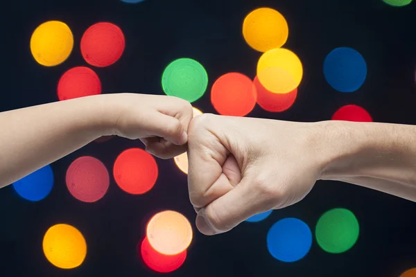 Pai e filho punhos de perfuração para acordo sobre luzes de Natal fundo . — Fotografia de Stock