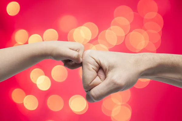 Father and son punching fists for agreement on christmas lights background. — Stock Photo, Image