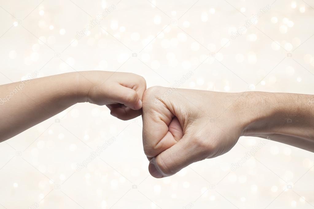 father and son punching fists for agreement on christmas lights background.