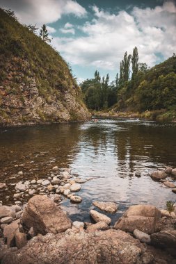 People bathing in the Durazno River in Cordoba Argentina, in the afternoon on a rocky cliff and vegetation in the background