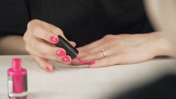 A young European girl paints her nails with pink nail polish — Stock Video