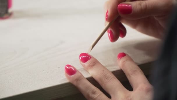 Uma jovem garota europeia pinta suas unhas com esmalte rosa — Vídeo de Stock