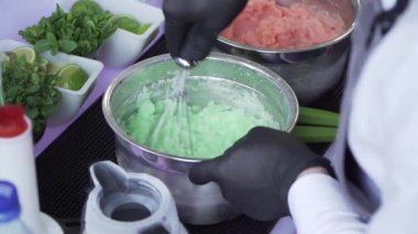 Yeşil fıstıklı dondurmayı metal kaseye karıştıran bir barmenin elleri.