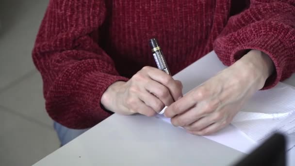 Жінка в червоному светрі, яка пише своє ім'я в чорному маркері на ігровій картці — стокове відео