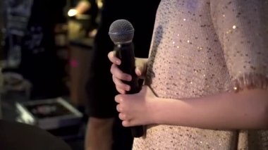 Çocuk konserinden önce elinde mikrofon tutan küçük bir kız.