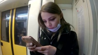 Avrupalı bir kız Moskova metrosuna biniyor.
