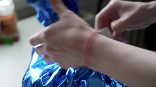 Fille européenne emballe un cadeau dans un emballage brillant bleu — Video