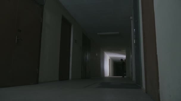 若い男が暗い廊下を歩いていて — ストック動画