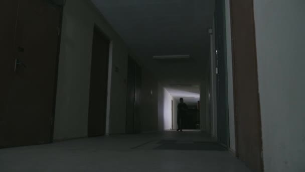 Un joven camina por un oscuro corredor — Vídeos de Stock