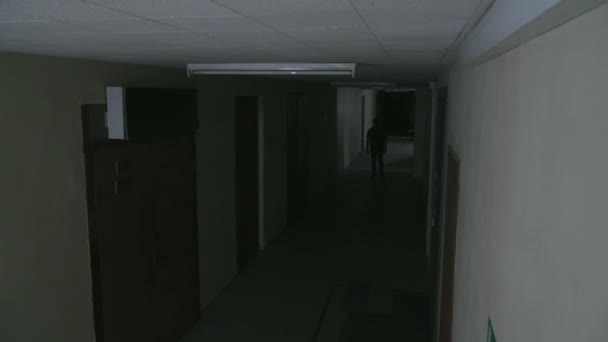 Un joven camina por un oscuro corredor — Vídeo de stock