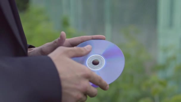 Een jongeman in een jasje draait een cd-speler — Stockvideo