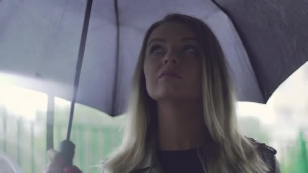 A young European girl stands with a black umbrella — Vídeo de Stock