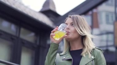 Genç Avrupalı kız bardaktan soda içiyor.