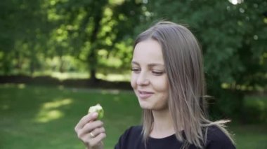 Genç kız yaz ormanında elma yiyor.