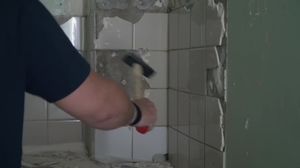 Hombre rompe azulejos blancos con un martillo — Vídeos de Stock