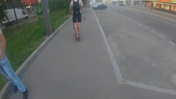 Молодой парень едет на электрическом скутере — стоковое видео