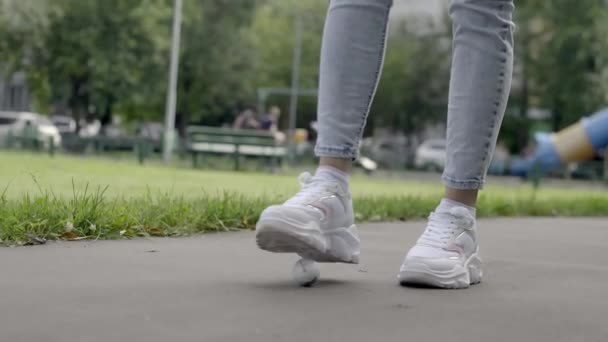 Beine eines jungen Mädchens in weißen Turnschuhen schlagen auf einen Golfball — Stockvideo