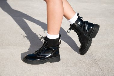 Şehir merkezinde siyah asker tarzı çizmeleri ve beyaz çorapları olan kadın modeller.