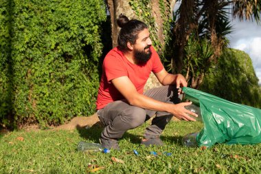 Adam geri dönüşüm için parktan plastik şişe topluyor..