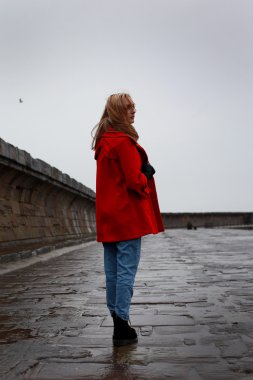 Genç kadın yağmur ve karla karışık yağmur ıslak bir eski iskele üzerinde