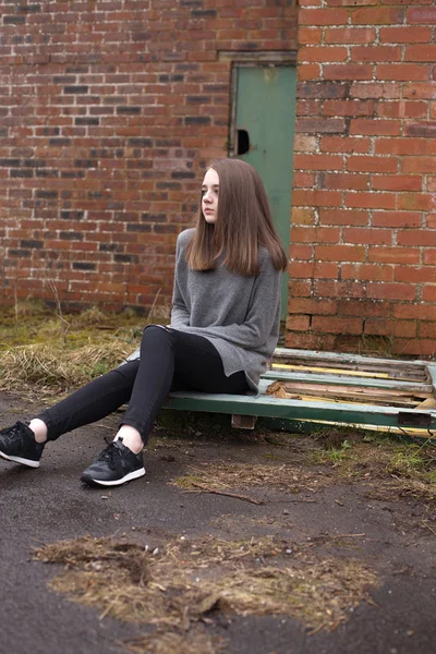 Досить молода дівчина-підліток сидить на деяких старих дверях — стокове фото