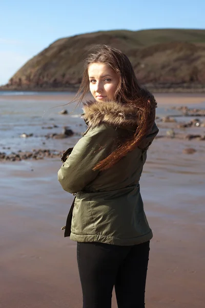 Mladá žena na pláži všechny zabalené proti chladu — Stock fotografie