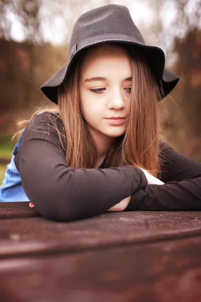 Vrij tienermeisje zitten buiten op een picknicktafel — Stockfoto