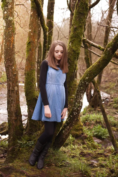 Bonita adolescente apoyada contra un árbol con un río en la b — Foto de Stock